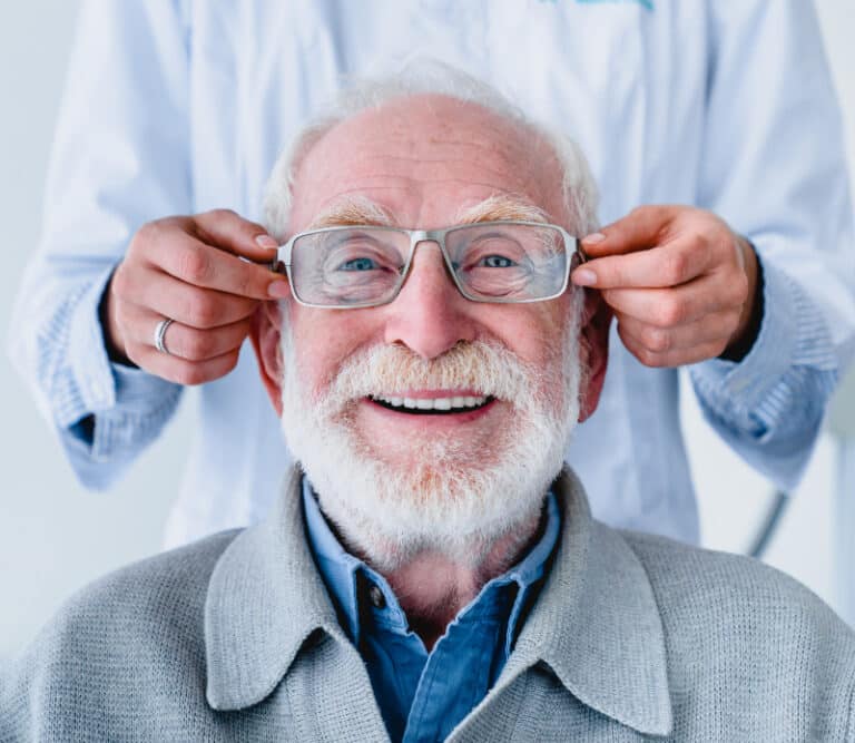 Doctor fitting glasses on cheerful aged male patient: cropped photoDoctor fitting glasses on cheerful aged male patient: cropped photo