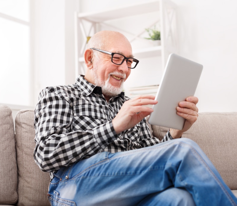Senior man reading news on digital tablet