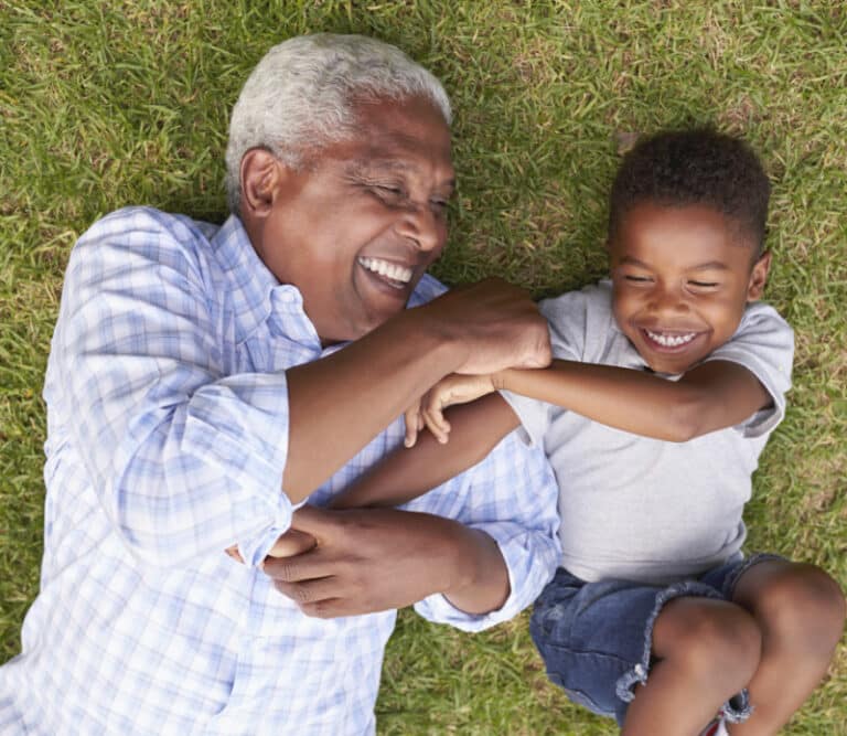Grandfather and grandson play lying on grass, aerial view